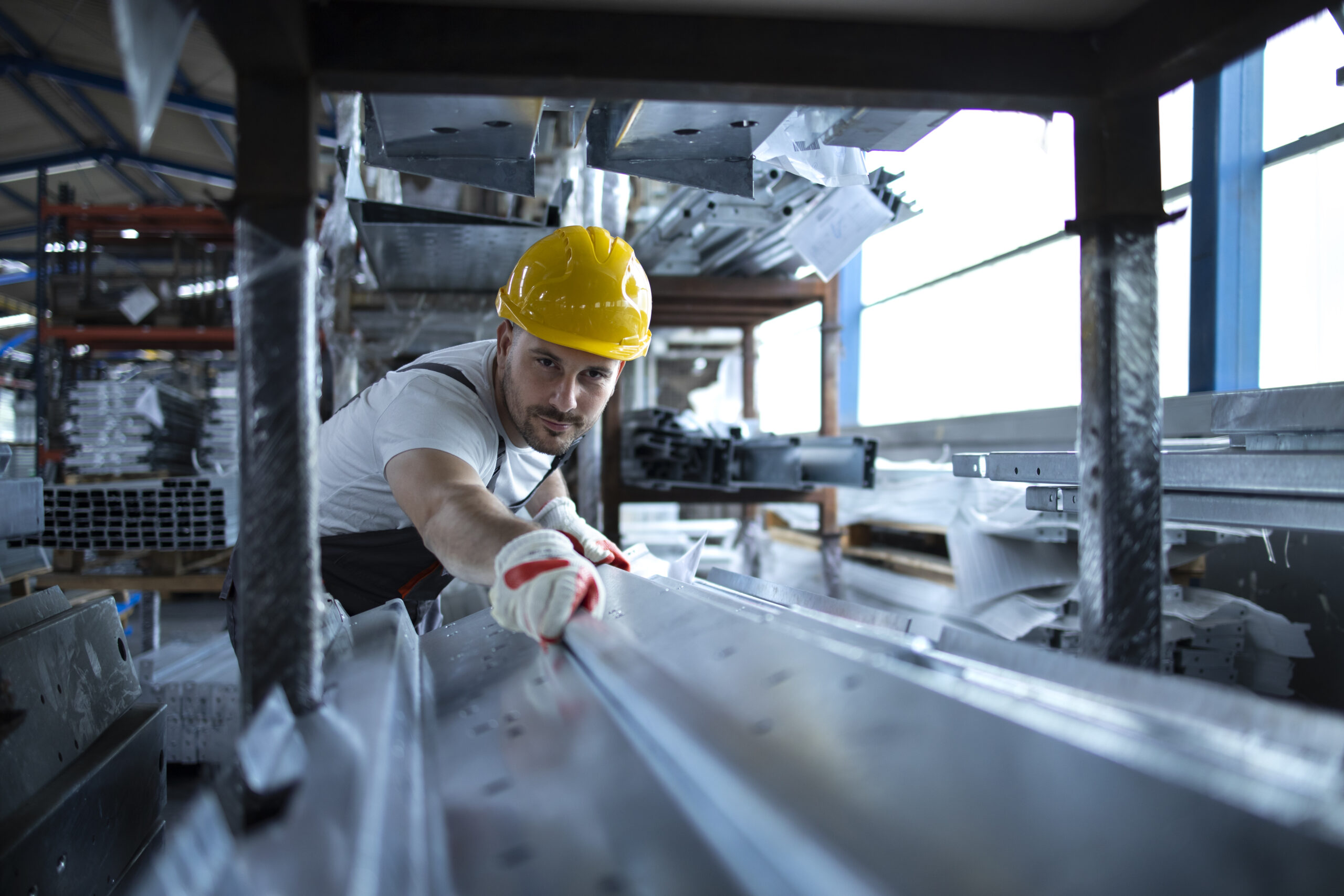 Factory worker working in warehouse handling metal material for production.